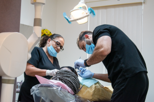 Dr. Alameen and Nurse cleaning a patients teeth.